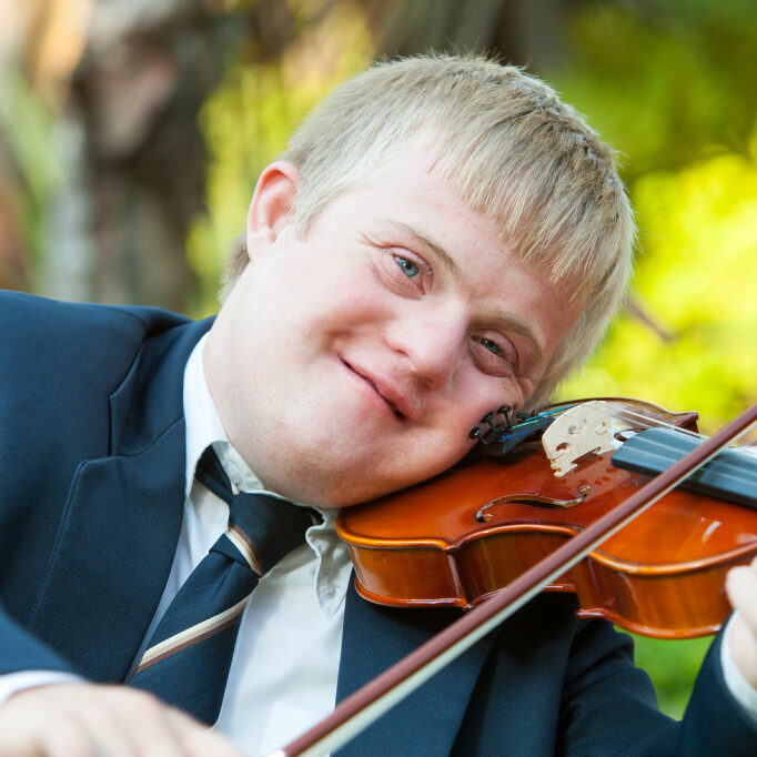 Portrait of young handicapped violinist practicing outdoors.